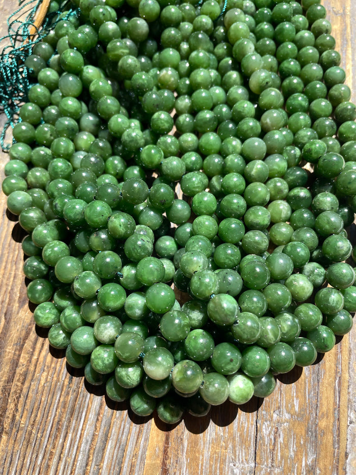 Pile of 8mm green jade beads ready for stringing on a wooden surface