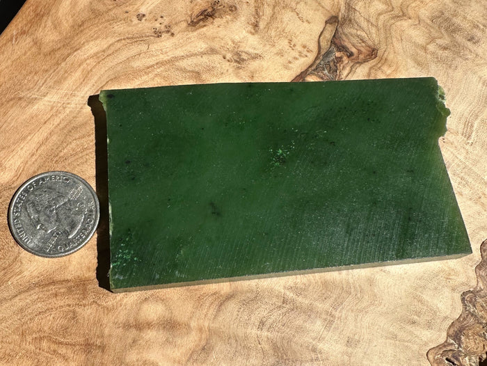 green jade slab on wooden base beside a quarter