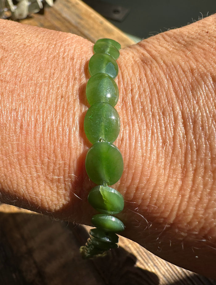 Close up of a green jade lentil bead bracelet worn on the wrist.