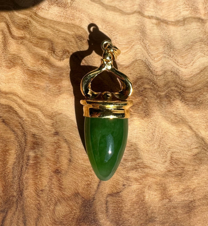 AA Canadian Pendant 0212 gold pendant with green teardrop gemstone and ornate top on wood grain background