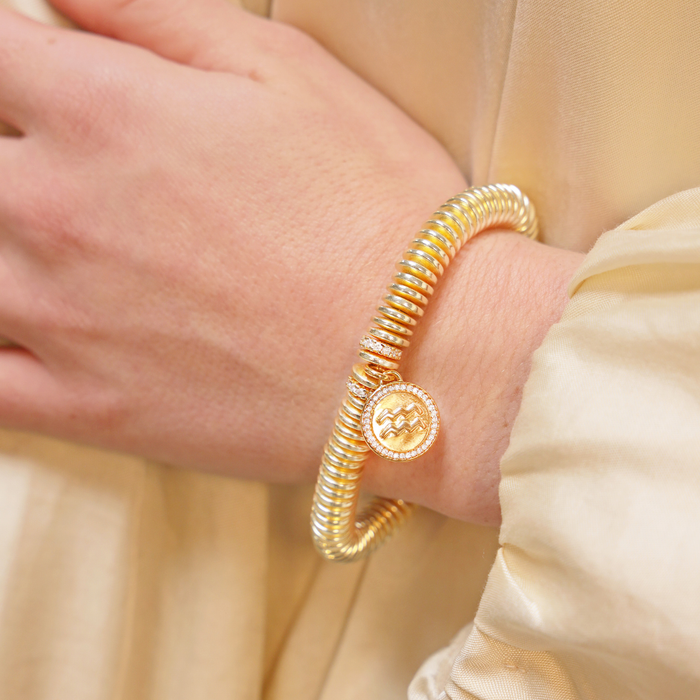Gold bracelet on a wrist with a soft beige background