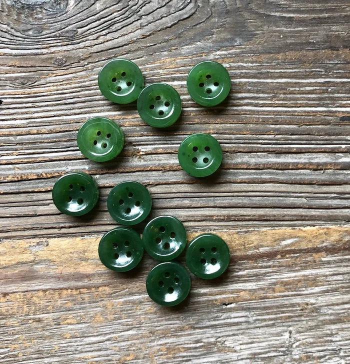 Green round buttons with four holes scattered on a weathered wood background