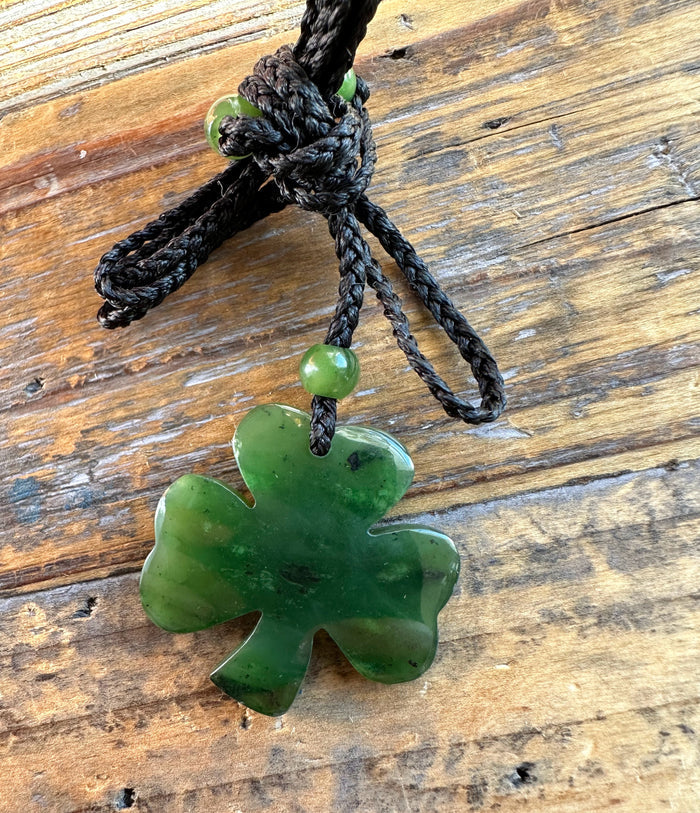 Close up of Canadian Jade 3 leaf clover pendant on a knotted black cord with green beads