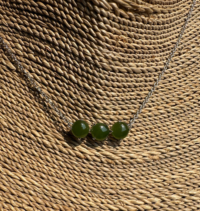 Canadian Jade and Silver three bead necklace laid on a woven mat with three green jade stones on a silver chain
