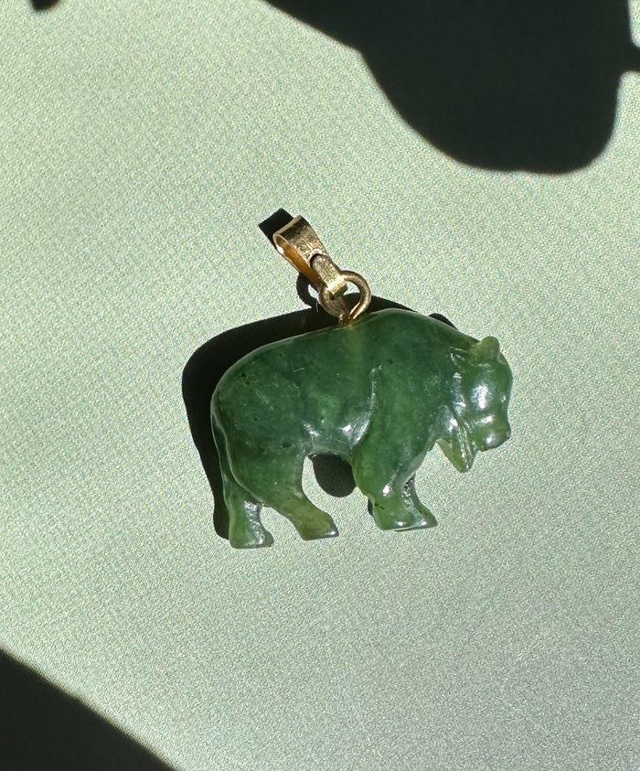 Canadian Jade Bison Charm pendant in green jade with a metal bail on a light background