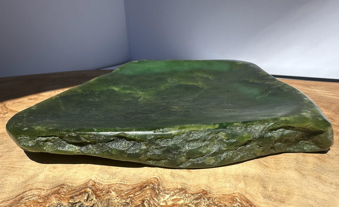 Large green stone on a wooden surface with a neutral background