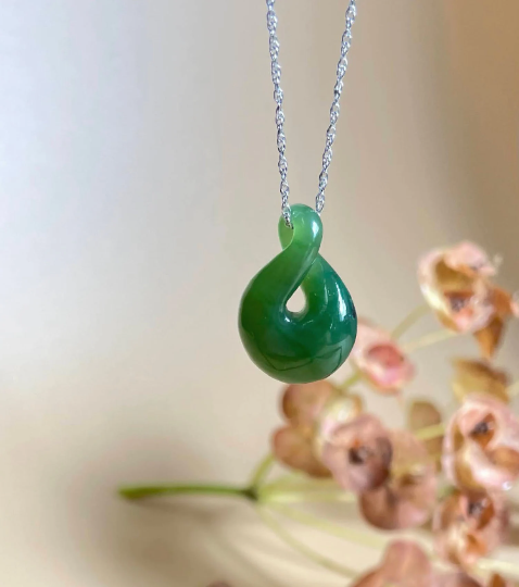 Green jade infinity twist pendant on a silver chain.
