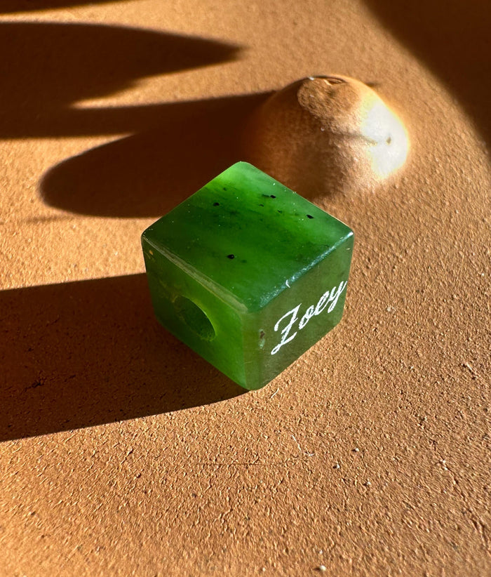 Green jade cube pendant with Zoey engraved on the side and a top hole