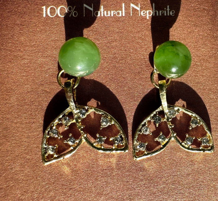 Pair of whale tail earrings on a brown burgundy backdrop with green nephrite beads and crystal tails