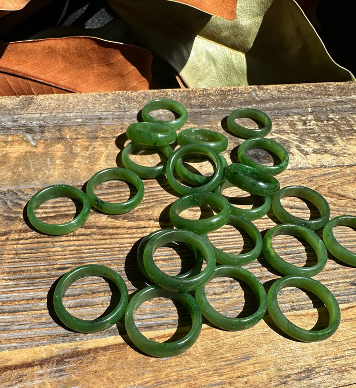 Green jade ring bands scattered on a weathered wooden surface