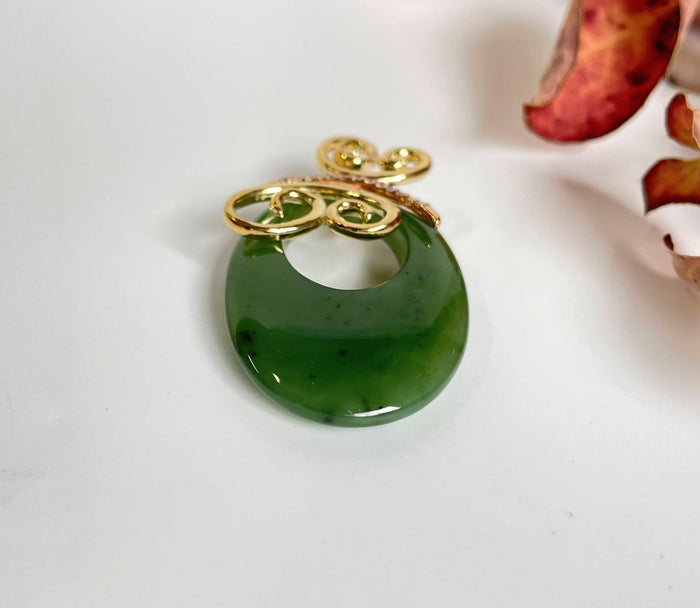 Jade Butterfly Pendant featuring green oval jade and gold decorative loops on a white surface