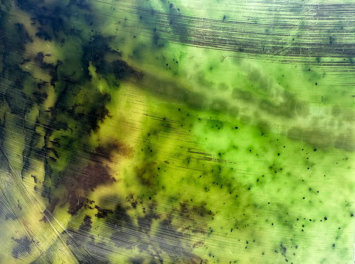 Abstract textured print with a mottled pattern of lime green, yellow, and dark charcoal gray, featuring fine horizontal lines and organic splatter details.