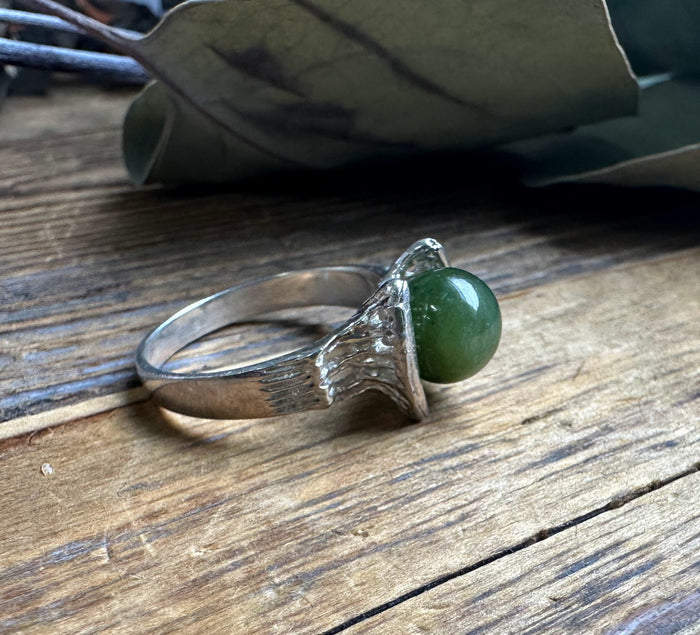 Silver ring with a green jade ball in a jagged textured bezel inspired by a starship design
