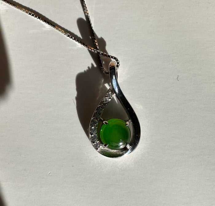 Silver teardrop pendant with a green jade bead and diamond accents on a chain