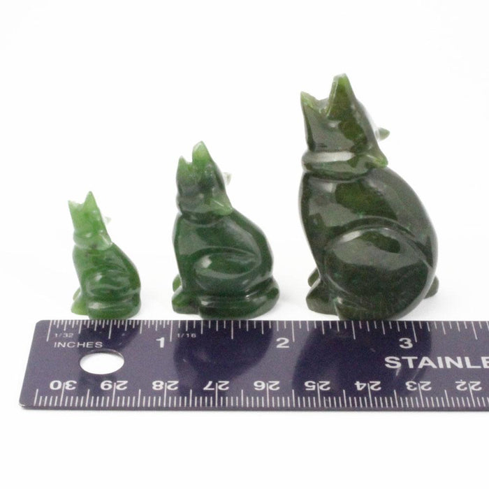Three green jade wolf figurines in varying sizes arranged with a ruler for scale