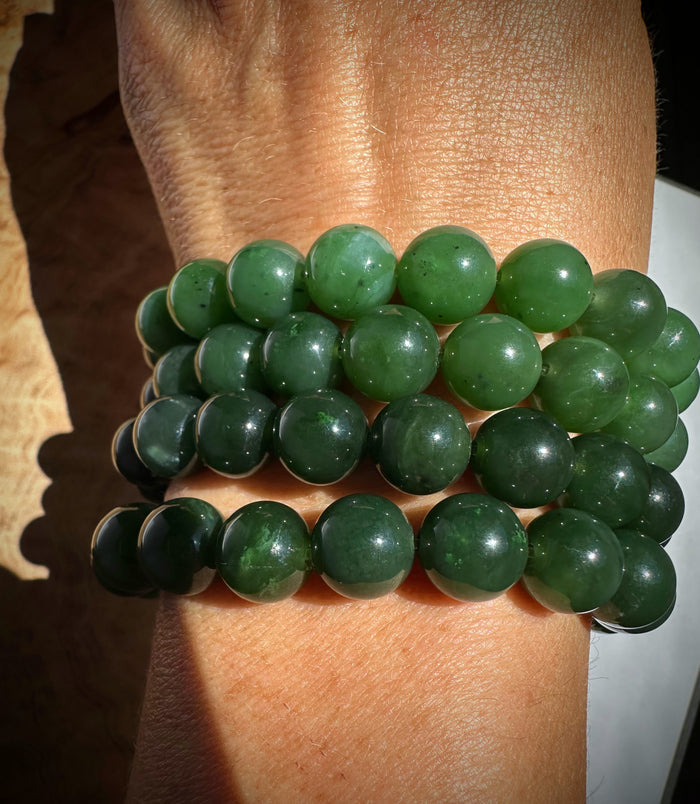 Green beaded bracelet on a wrist with a neutral background