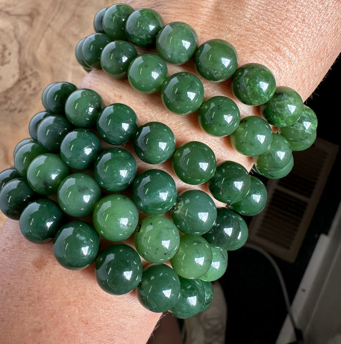 Green jade beads on a wrist against a wooden background
