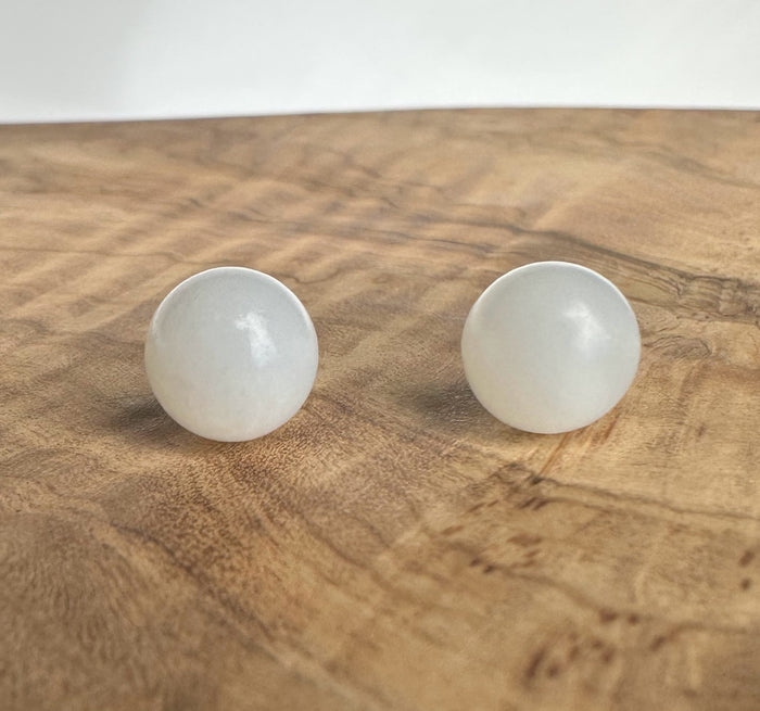 round white jade stud earrings on wood display