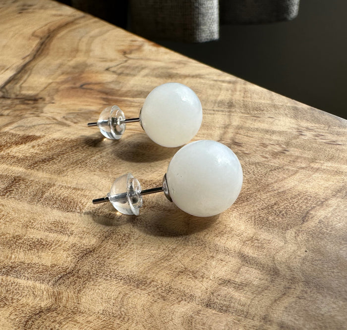 white jade stud earrings on a wooden base