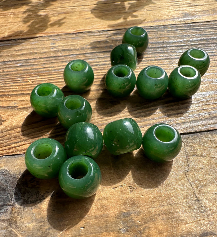 Green round beads with central holes scattered on a weathered wooden surface
