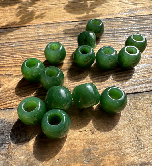 Green round beads with central holes scattered on a weathered wooden surface