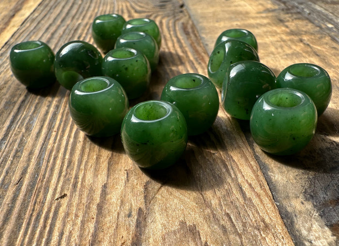 Glossy green beads with holes arranged on a wooden surface