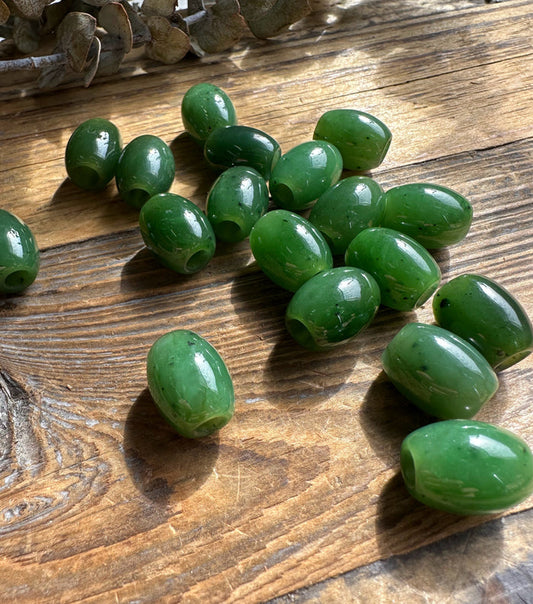 Green oval beads with central holes on a wooden tabletop