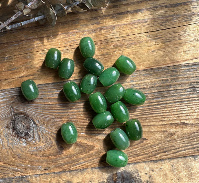 Green 12x15mm oval beads scattered on a rustic wooden surface