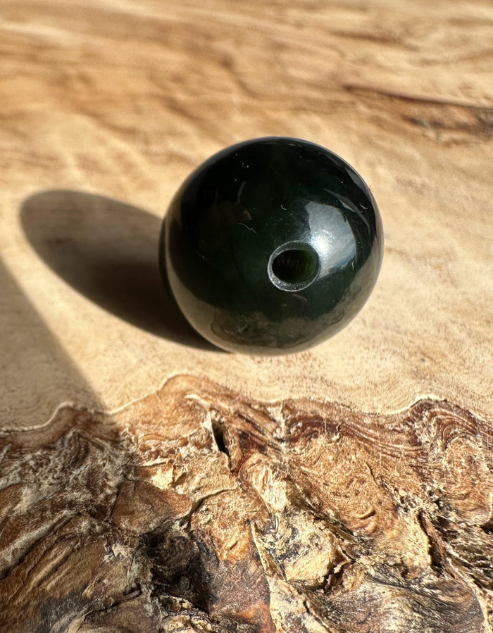 Dark green nephrite jade bead drilled through the center
