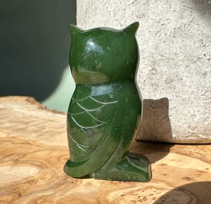 Back view of the two inch dark green jade owl figurine with carved feather details.
