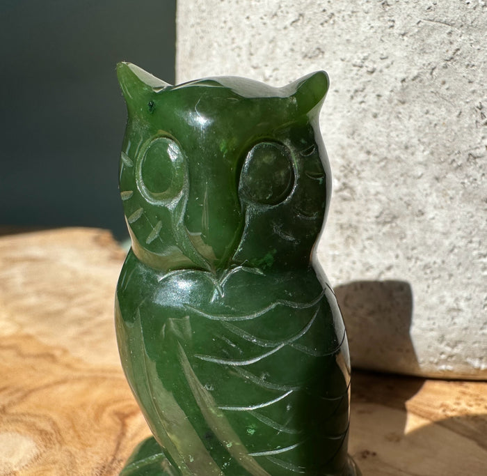 Slight front angle of the two inch dark green jade owl with glossy finish and feather carvings.