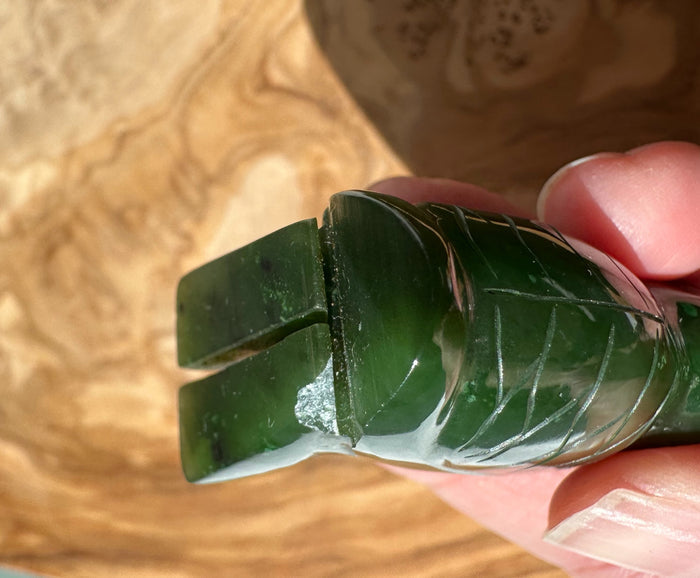 Chipped dark green jade owl pendant with carved feather details