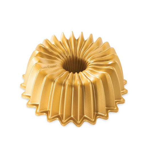 Bright gold bundt pan with fluted sides and hole in middle on white background; "NORDIC WARE" logo stamped on bottom of pan