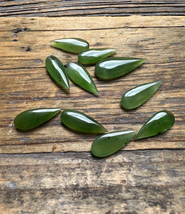 Green teardrop cabochons arranged on a weathered wooden surface