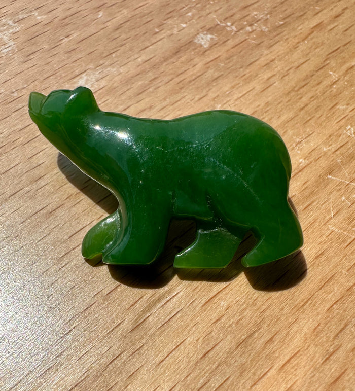 Green jade bear brooch shown from the side with rounded body and sculpted paws