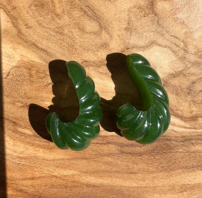 Pair of green Canadian jade fluted curved pieces on a wood surface