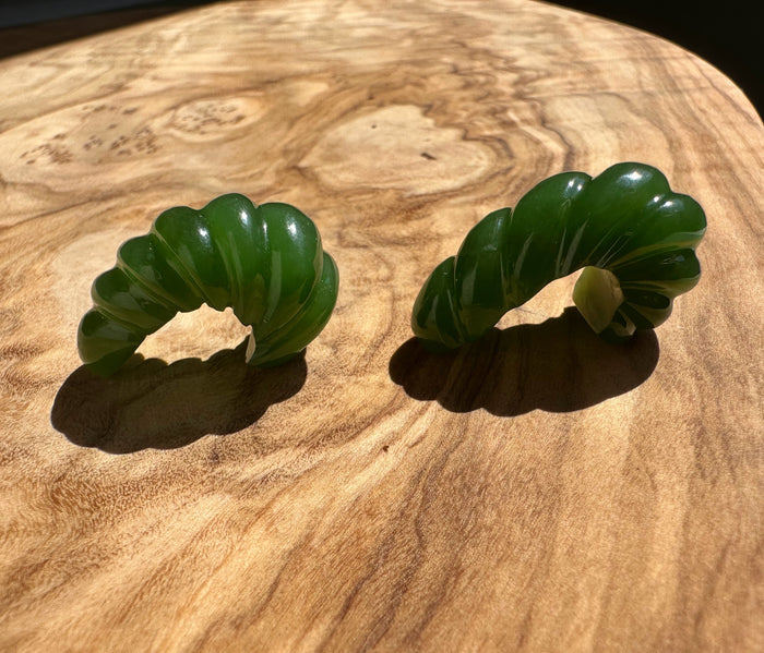 Top-down view of green jade fluted curved pair on wood showing scalloped edges