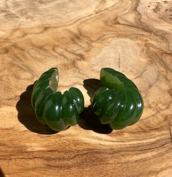 Separated green canandian jade fluted pair on a wooden surface