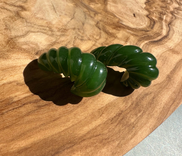 Green Canadian jade fluted piece resting on a wood surface
