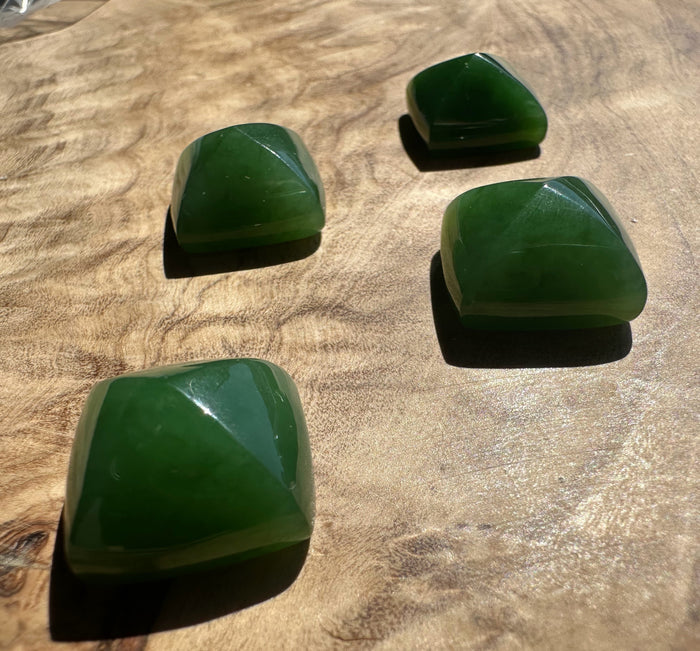 Four green stones on a wooden surface