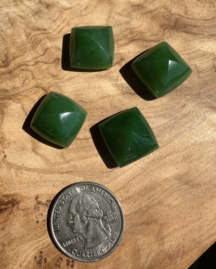 Four green square stones on a wooden surface with a quarter for scale.