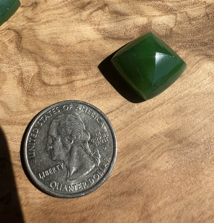 Green stone next to a U.S. quarter dollar on a wooden surface