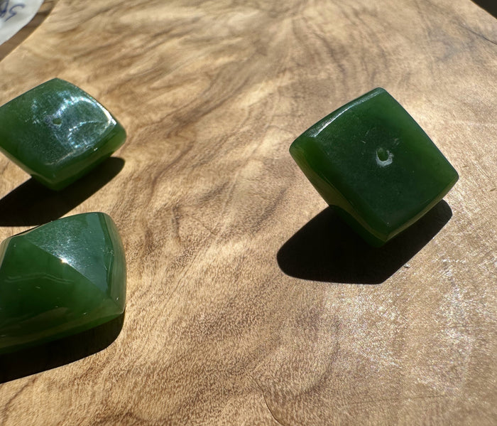 Three green jade stones on a wooden surface