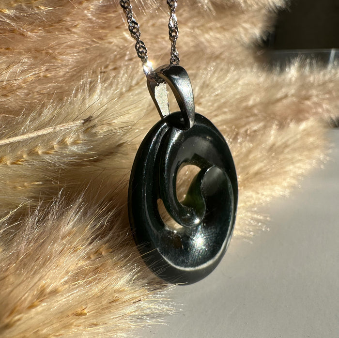 Black nephrite jade koru pendant with a spiral opening on a silver chain