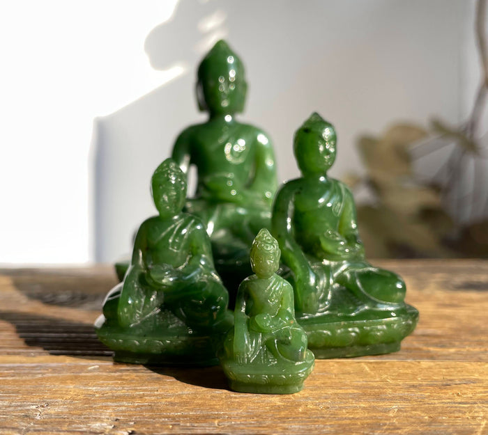 Green jade Buddha statues in varying sizes arranged on a wooden surface