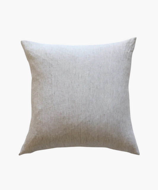 A square, light beige pillow with a textured fabric surface is shown against a plain white background. The pillow has a soft, minimalist feel. | Wildwood Home Co.
