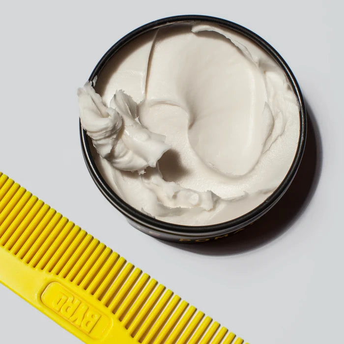 BYRD matte pomade i svart metallboks med gul BYRD-kam, kremet tekstur