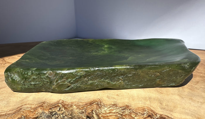 Large green stone on a wooden surface with a neutral background