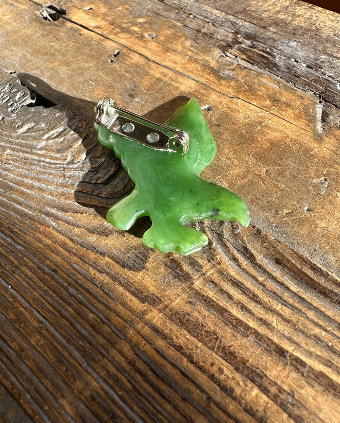Angled side view of jade eagle brooch highlighting carved wings and attachment base