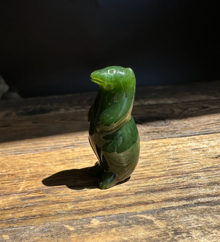Canadian Jade Otter figurine standing upright on a sunlit wooden surface
